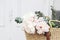 Feminine wedding still life composition. Straw French basket bag with pink peonies flowers and eucalyptus bouquet. Old