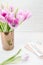 Feminine workspace. Bright and airy desk top with notepad and pink tulips. Vertical