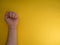 Feminism. Female fist on a yellow background. Top view, minimalism