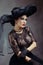 Femme fatale woman in black lace dress and black fansy hat