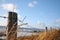 Fence along a beach, surrounded by grass on a sunny day with blu