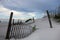 Fence buried in sand dunes and pretty skies