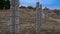 The fence of concrete pillars and rusty barbed wire.