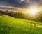 Fence on hillside meadow in mountain at sunset