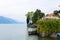 Fence with ivy near house with Italy flag, lake Como and Alps mountain in background.