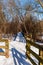 A fence lined entry way to a wooden walkway covered with snow in Frick Park located in Pittsburgh, Pennsylvania, USA