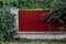 Fence made of panels of red corrugated sheet metal with grass in front and trees behind it
