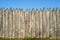 Fence made of sharp wooden stakes against the blue sky. Wooden fence vertical logs pointed against the sky protection against inva