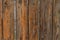 A fence of old boards of brown color with peeling varnish