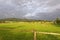 Fence overlooking a lush green grassland with haystacks placed in multiple spots