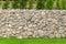 Fence real stone wall surface with cement on green grass field