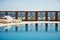 Fence of the resort pool reflected on the water. Pure blue sky on the background.