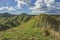 Fence on steep hill under cloudy sky at Tahora Saddle along the Forgotten World Highway in New Zealand.