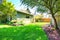 Fenced back yard with child\'s swing sit and green shed behind.