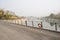 Fenced bridge with tarred roadway over river in sunny winter aft