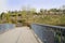 Fenced footbridge before blossoming hillside in sunny spring