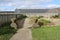 A fenced garden with plants and stone planters outside a restored home in the historical garrison town of Louisbourg Cape Breton