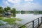 Fenced and planked footbridge over lake with boats and modern ci