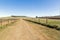 Fenced Rural Farm Dirt Road Running Next to Meadow