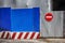 Fencing of construction site with red construction light on the background of blue profiled sheet fence and stop sign