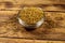 Fenugreek seeds in glass bowl on wooden table