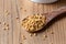 Fenugreek seeds on a wooden spoon on a table