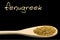 Fenugreek on wooden spoon isolated on black background. Latin name Trigonella foenum-graecum