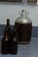 Fermented beer in a demijohn with airlock and dark bottles in kitchen