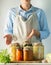 Fermented and canned vegetables various cans stand on the table and a woman cook in an apron. Recycling Autumn Harvest