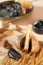 Fermented garlic head and garlic clove on a handmade wooden plate. A small clay bowl with black garlic paste in the background.