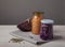 Fermented red and white cabbage in glass jars and a head of red cabbage on a white wooden table on a gray background