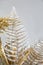 Fern branch covered with silver paint, interior decoration with gilded plants, home decor. Floral design, shiny sparkling fern