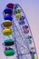 Ferris wheel with brightly colored multicolored cabins against the blue sky