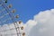 Ferris wheel cab rotating high above the ground against a cloudy blue sky