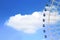 Ferris wheel cab rotating high above the ground against a cloudy blue sky