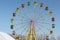 Ferris wheel with color cabins against the blue sky