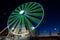 Ferris wheel with colored lights in `Porto Antico` harbor zone in Genoa, Italy