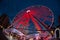 a ferris wheel illuminated in red color overview at night