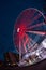 a ferris wheel illuminated in red color overview at night