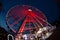 a ferris wheel illuminated in red color overview at night