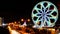 The ferris wheel known as the MOA Eye, is illuminated at night taken using a slow shutter speed in camera. The MOA Eye Ferris
