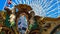 Ferris Wheel and Merry-go-round in an amusement park during the day with bright blue sky and white Ferris wheel paint