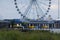 Ferris wheel and other amusements on a pier over the beach and ocean near a beach bar
