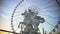 Ferris wheel rotating behind marble statue of equestrian riding winged stallion
