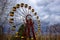 A Ferris wheel with yellow cabins against a cloudy sky