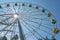 Ferris wheel with yellow and green booths against a blue sky