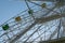 Ferris wheel with yellow and green booths against a blue sky