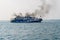 Ferry boat of Bay of Bengal smoke coming from its chimney. Black exhaust fumes coming from the chimney of a moored tanker.