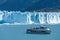 Ferry boat in front of Perito Moreno glacier, blue ice burg glacier from peak of the mountain through the blue lake in Los