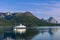 Ferry journey across calm fjord, verdant slopes and peaks under clear sky